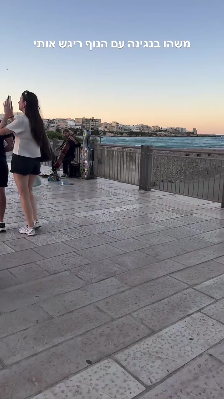 נגן צ'לו בטיילת מול השקיעה בפוליה