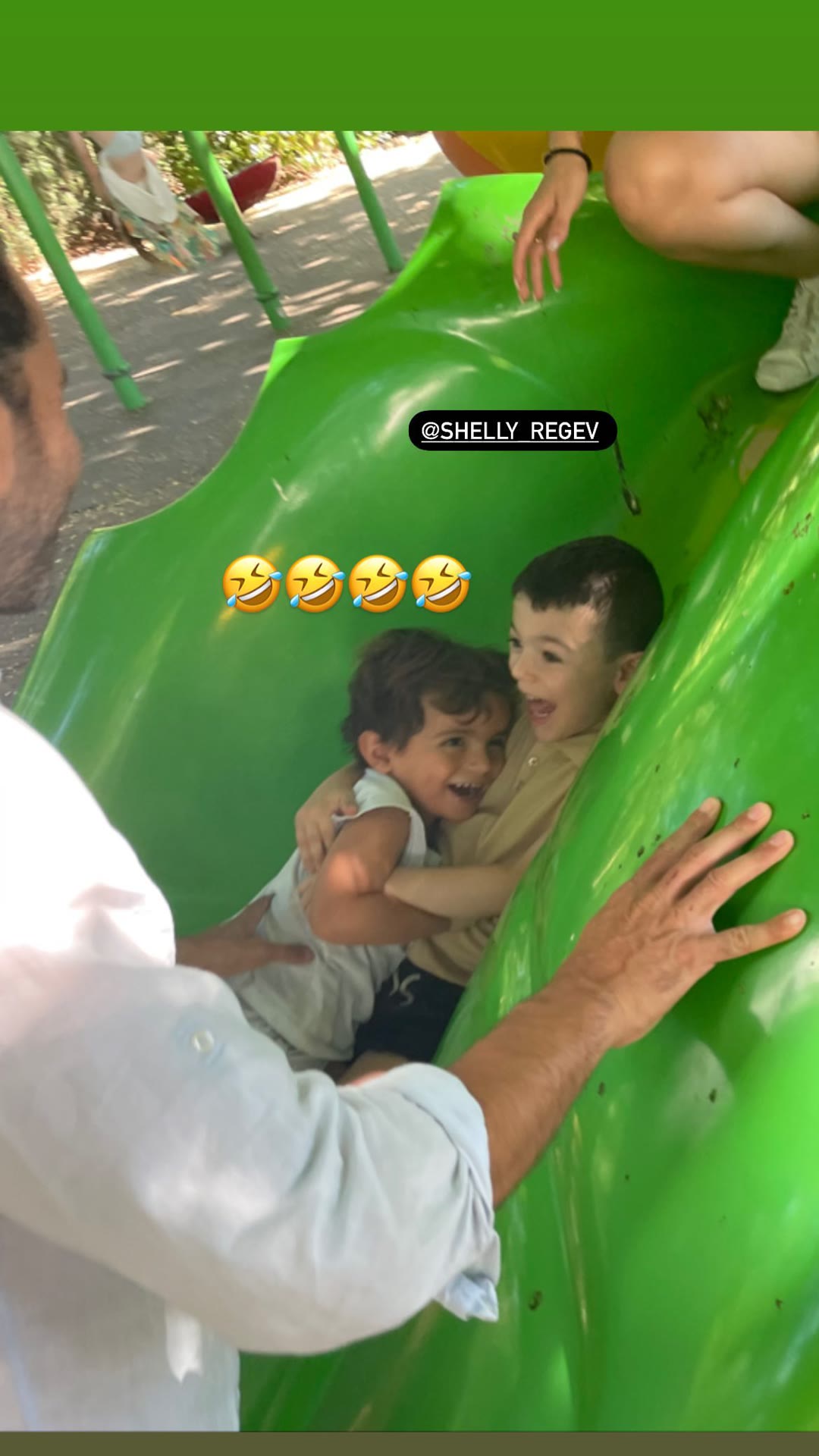 Kids stuck laughing in a green playground slide