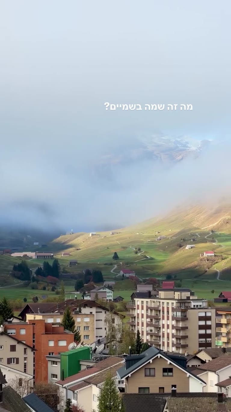 פסגה מבצבצת מהעננים מעל כפר בשווייץ
