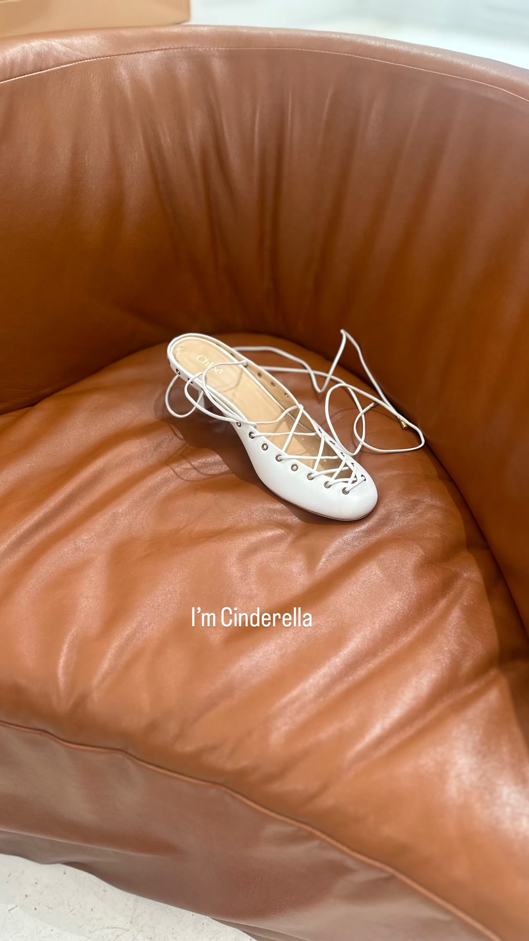 White Chloé lace-up flat left on a leather chair