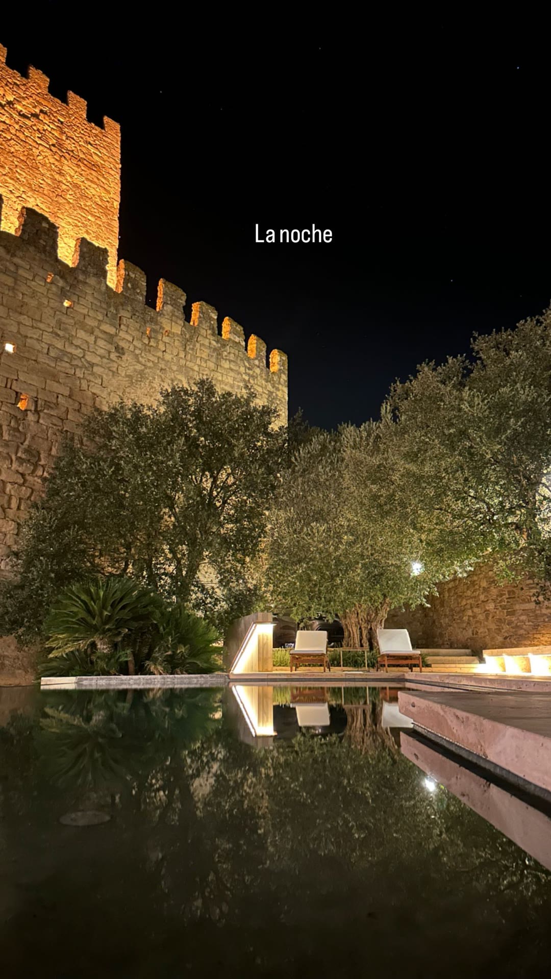 Pool under a lit castle wall at night, Spain