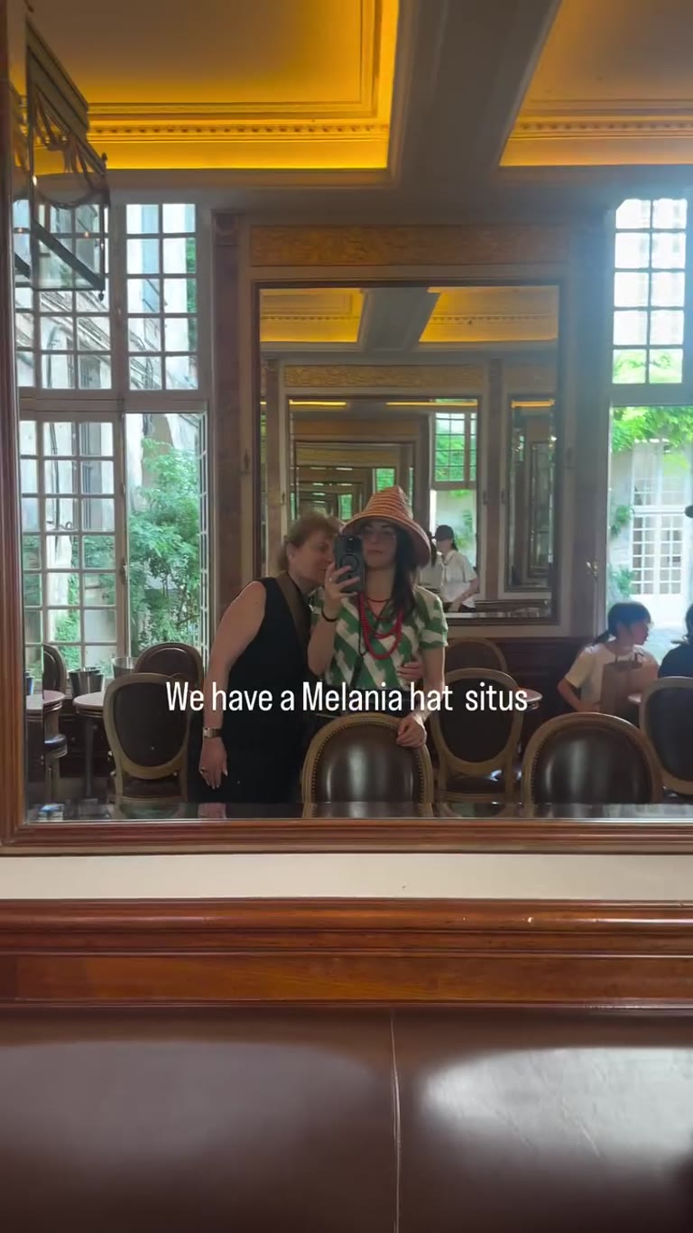 "Melania hat" mirror selfie in a Paris brasserie