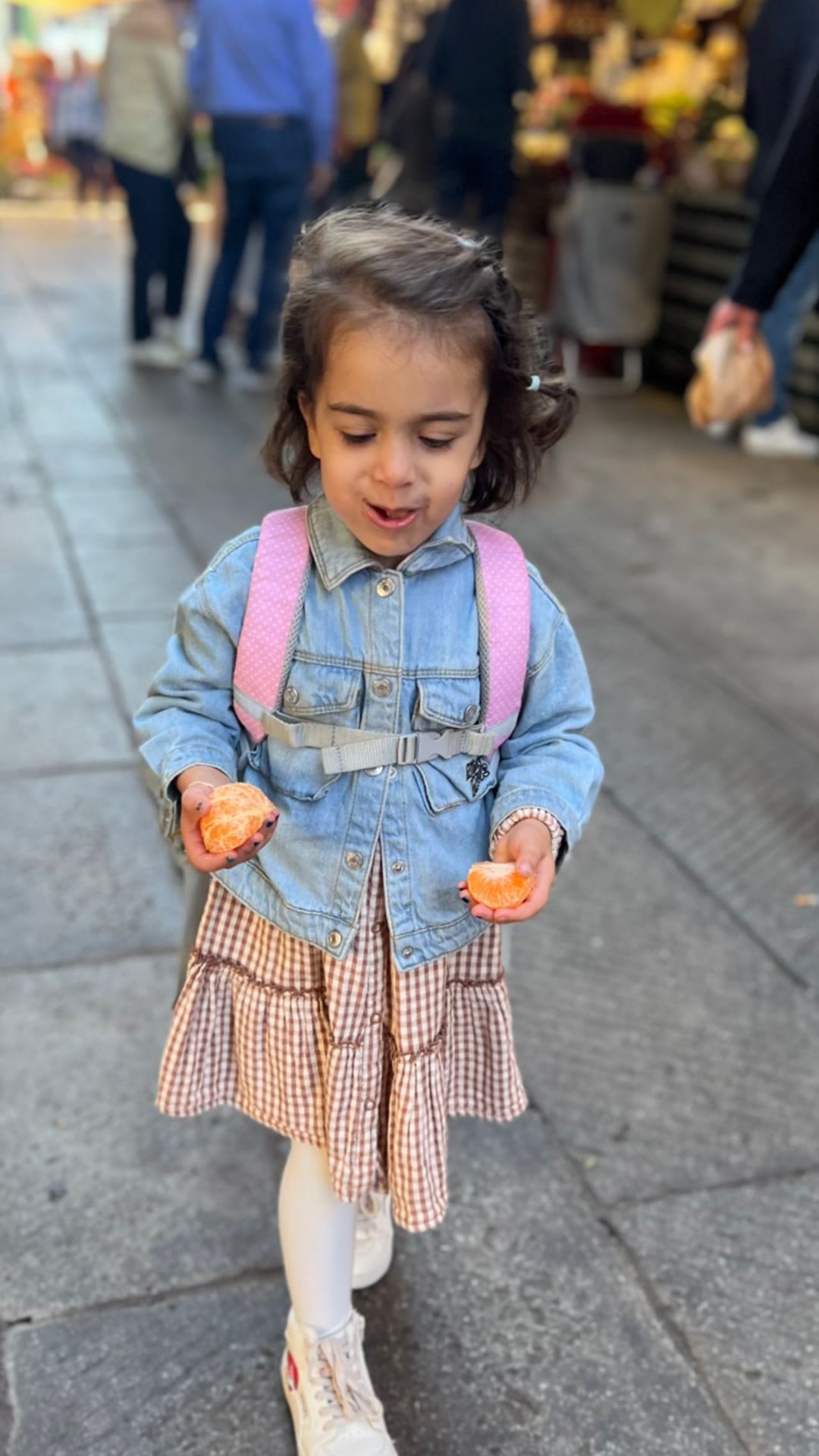 Toddler with a clementine at a Venice market