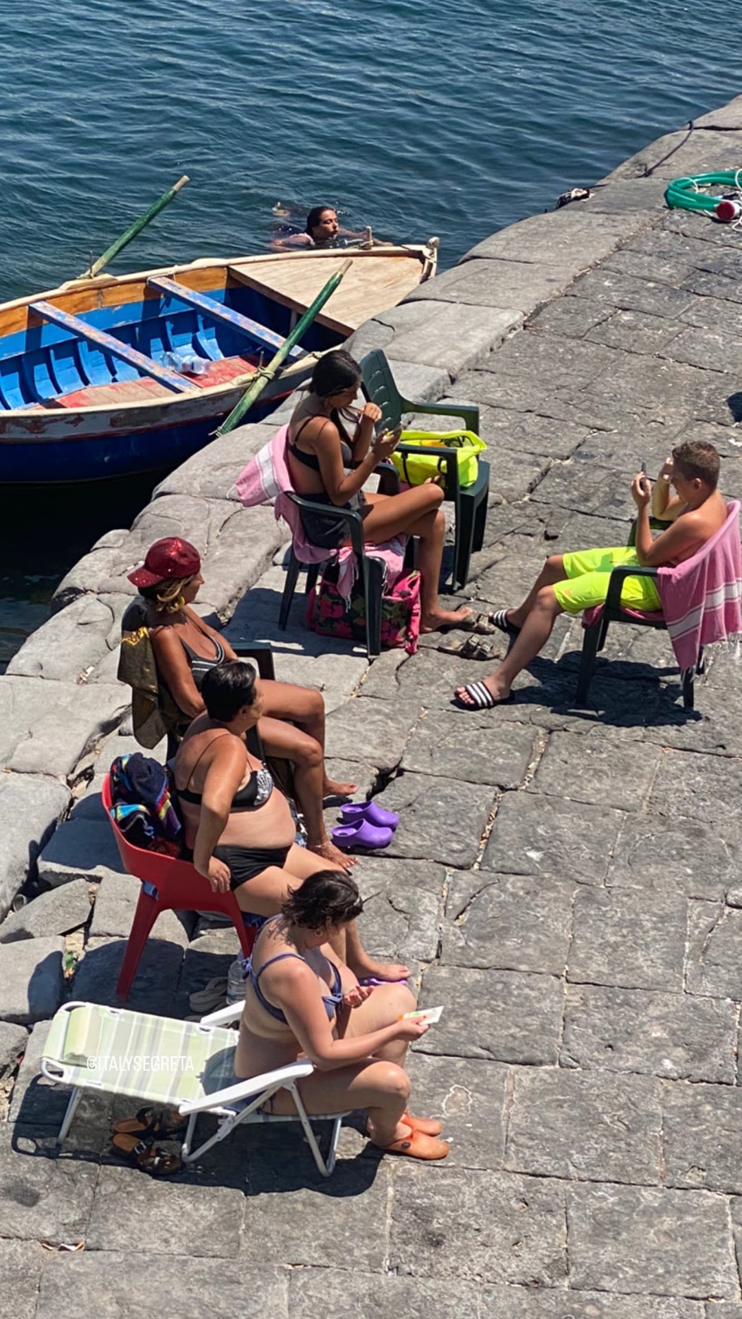 Locals sunbathing on a Naples stone quay