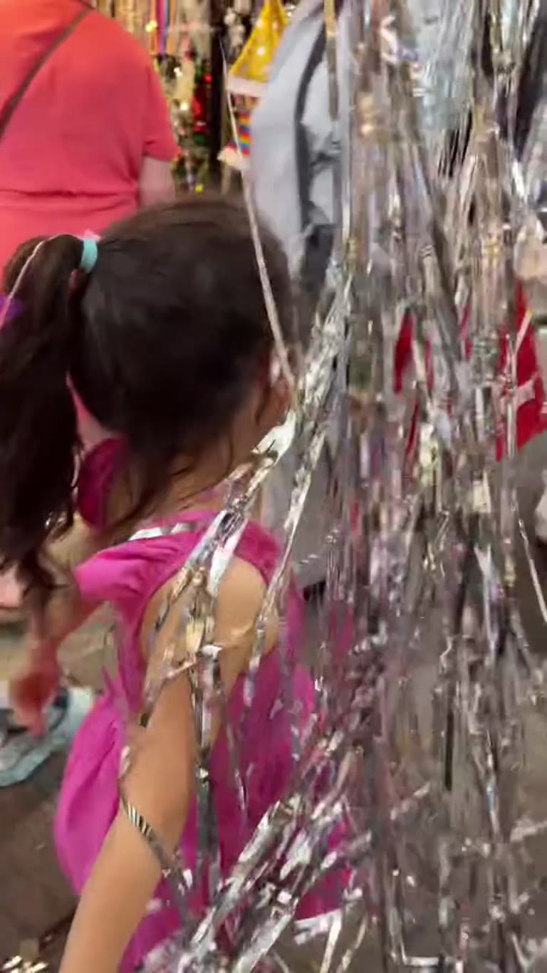Kid playing in tinsel at a Bangkok street market