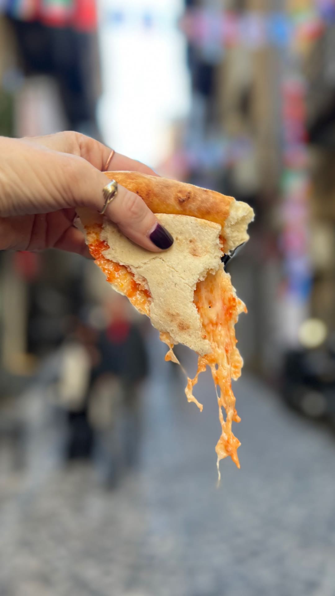 Cheesy pizza slice in Naples' old town alleys