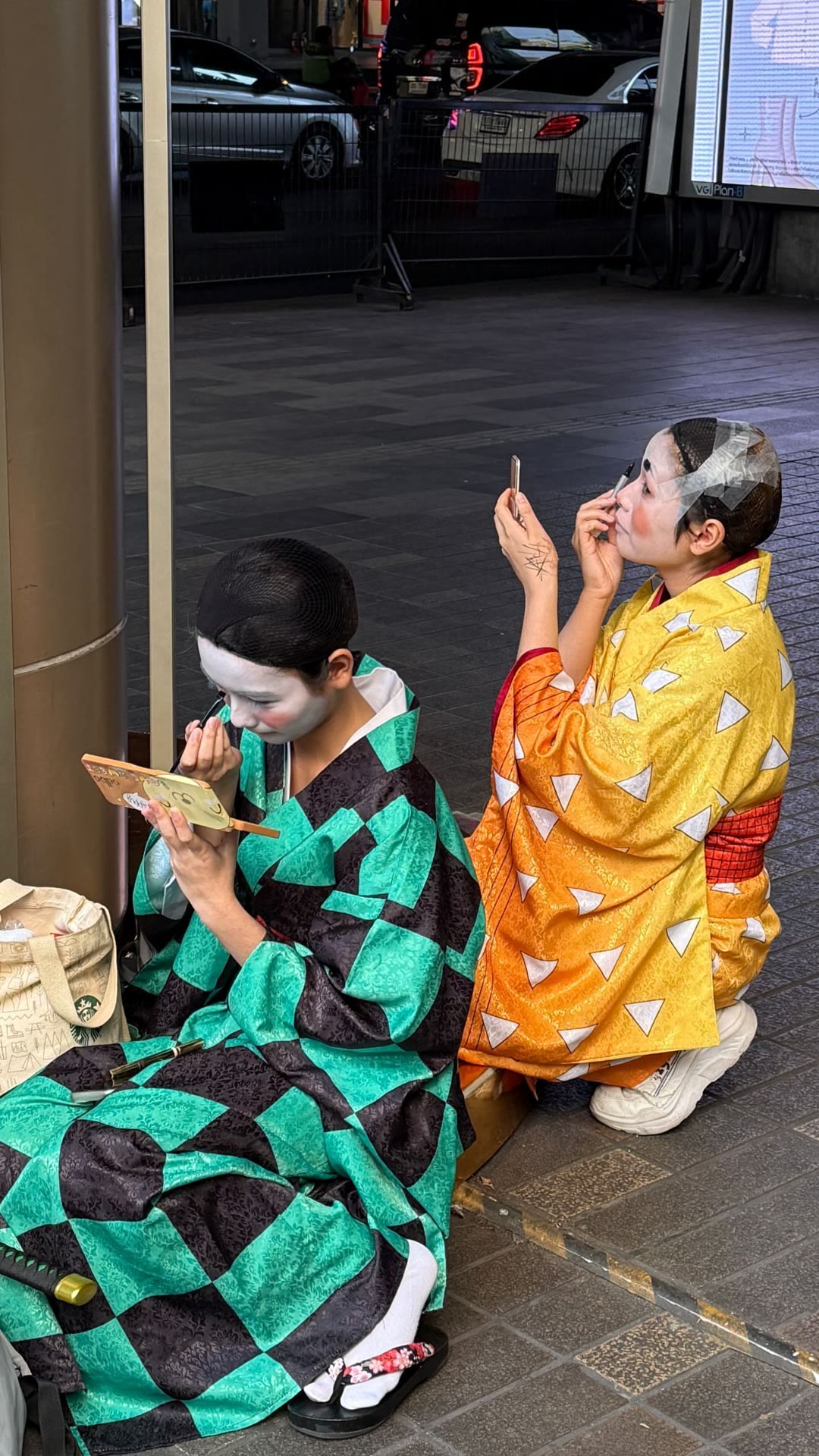 Kimono performers touching up makeup on a Bangkok street