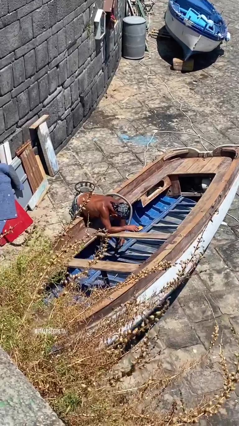 Fisherman mending a wooden boat, Naples