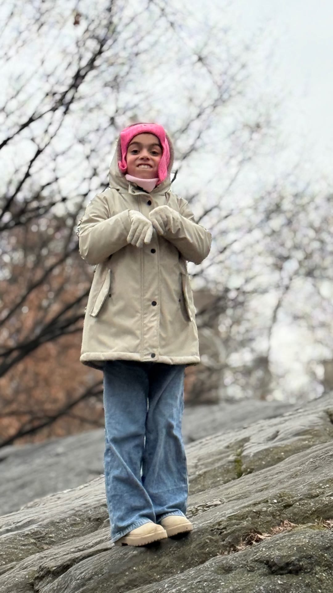 Kid bundled up on a rock in wintry New York