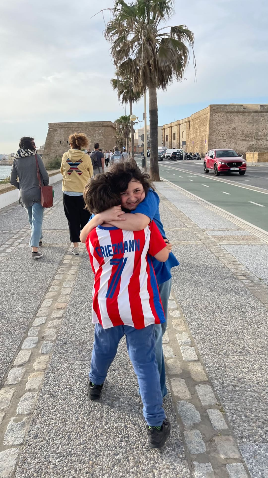 Kids hugging on the Cádiz seafront promenade