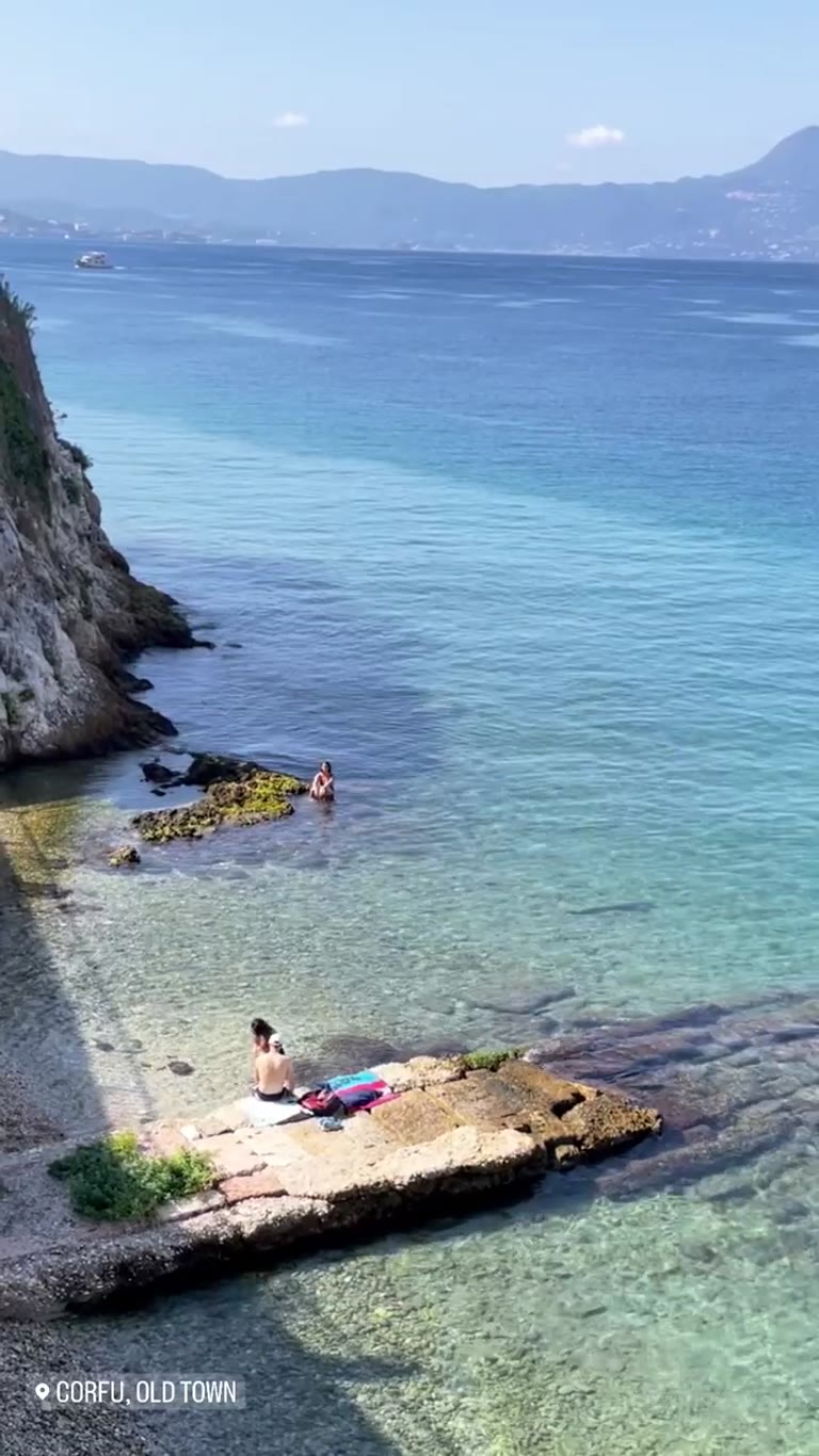 מפרץ שחייה צלול מתחת לצוקים בעיר העתיקה של Corfu